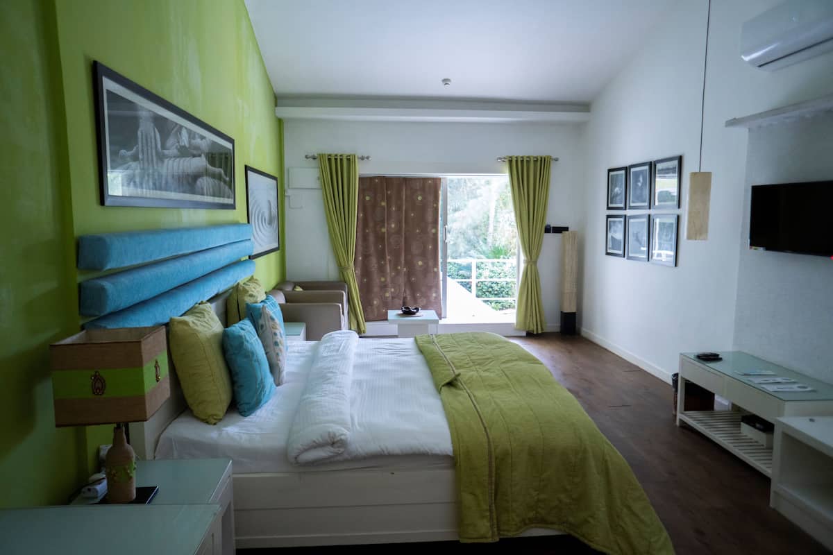 A hotel room with a bed, a nightstand, a TV, and a window with curtains.