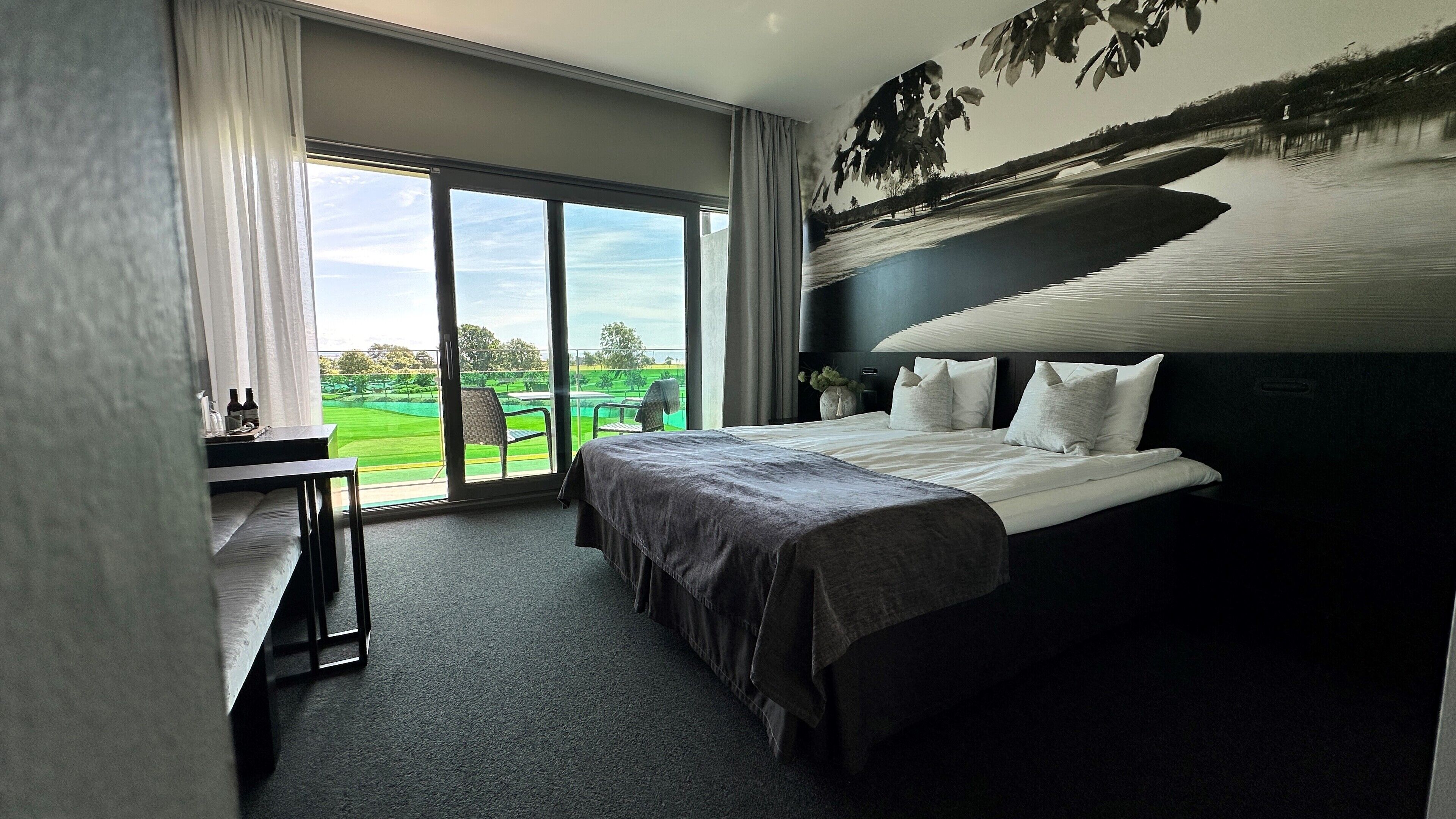 Una habitación de hotel con una cama grande, un escritorio y vistas a un campo de golf.