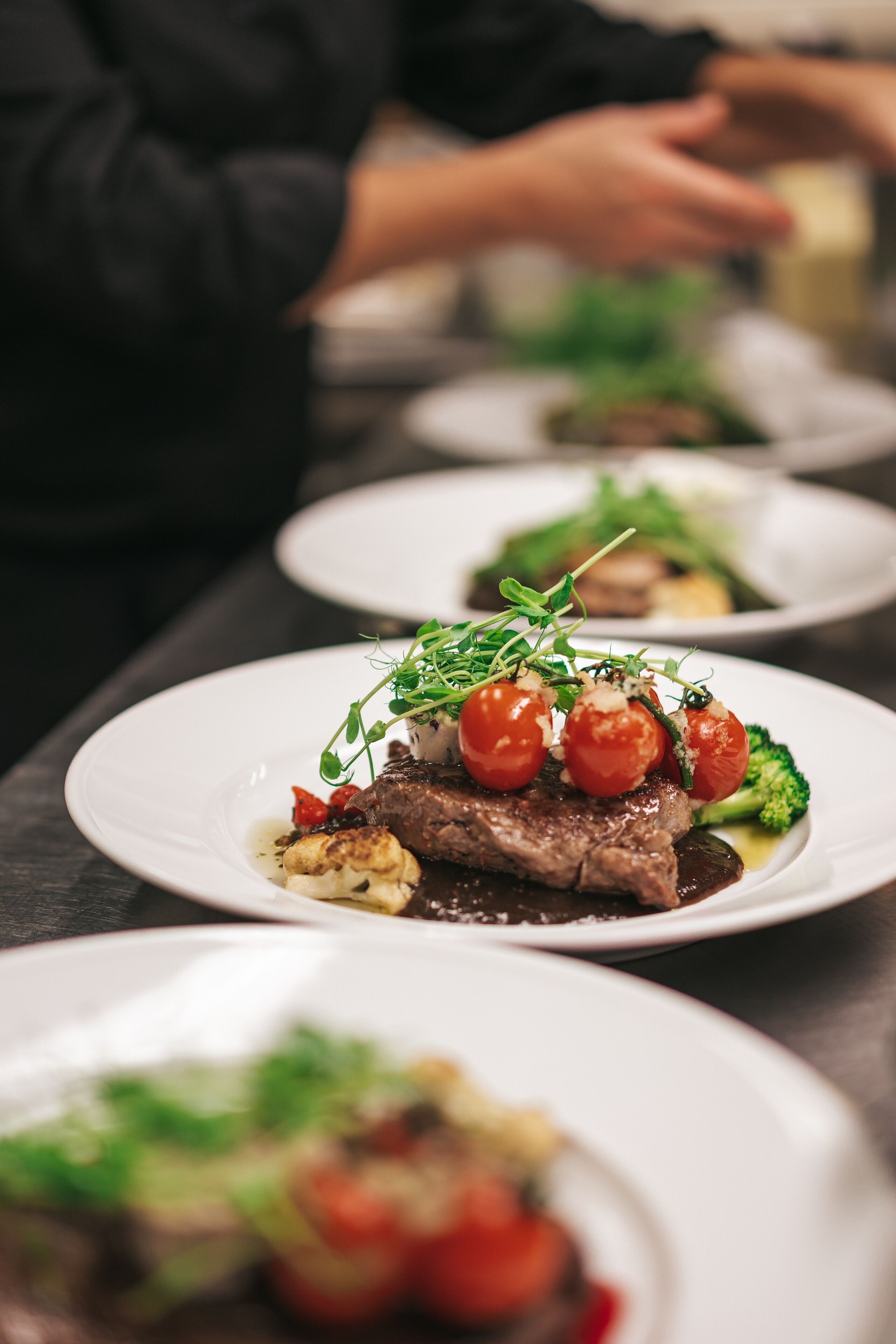 Una serie de platos con comida, incluyendo un filete con tomates cherry y vegetales verdes.