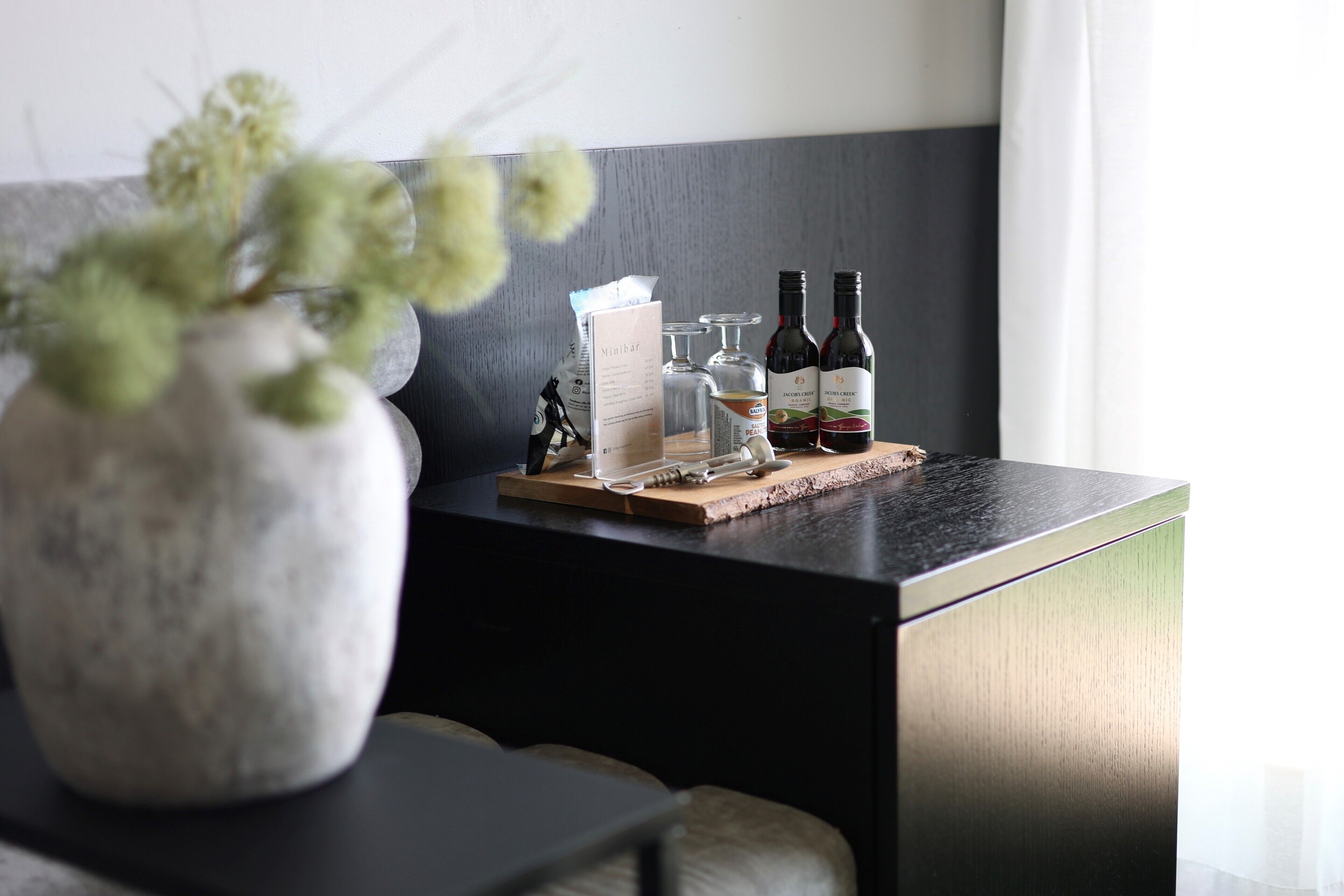 A modern kitchen with a marble countertop, a vase with green plants, a menu, and two wine bottles.