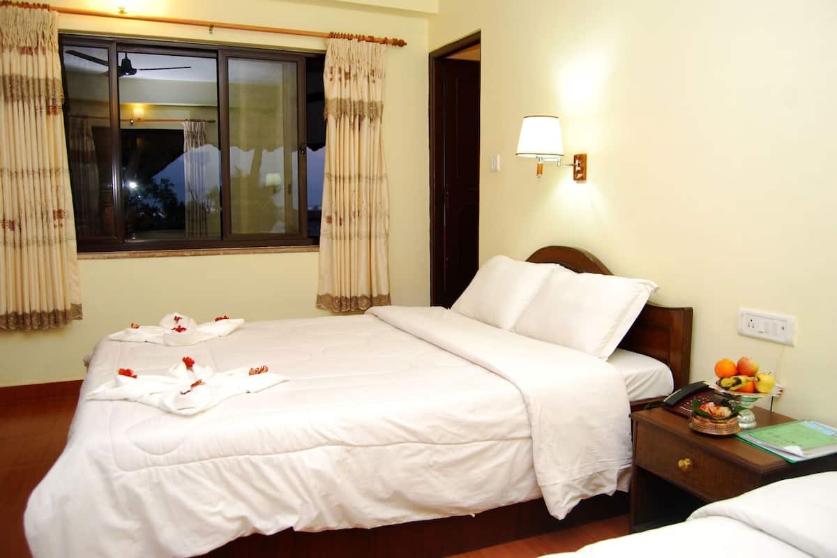 A hotel room with a bed, a nightstand with a lamp, a window with curtains, and a view of the outside.