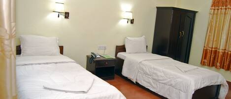 A hotel room with two single beds, a wardrobe, bedside lamps, and a telephone on the nightstand.
