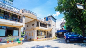 A two-story building with a balcony, potted plants, and a parked car. - Butterfly Lodge (Pokhara)