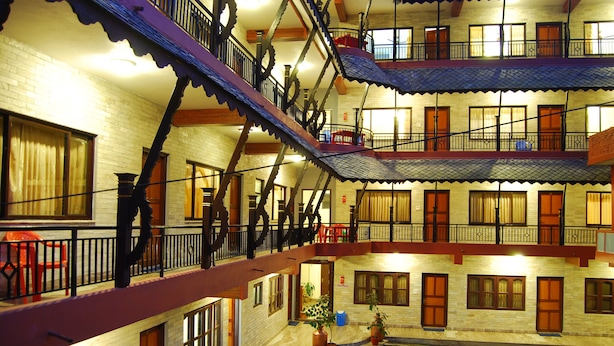 A multi-story hotel with balconies, a courtyard, and a brick facade. - Butterfly Lodge (Pokhara)