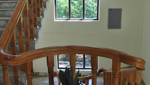 A wooden staircase with a marble floor, potted plants, and a view of greenery outside. - Butterfly Lodge (Pokhara)