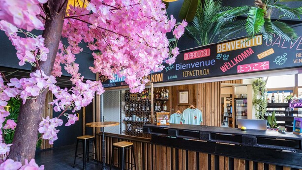 A bar area with a wooden counter, bar stools, and a sign with multiple languages. - greet hotel Limoges Nord (Limoges)