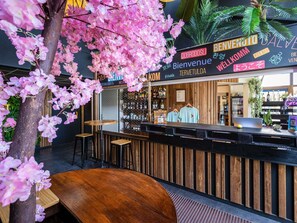A bar area with a wooden counter, bar stools, and a sign with multiple languages. - greet hotel Limoges Nord (Limoges)