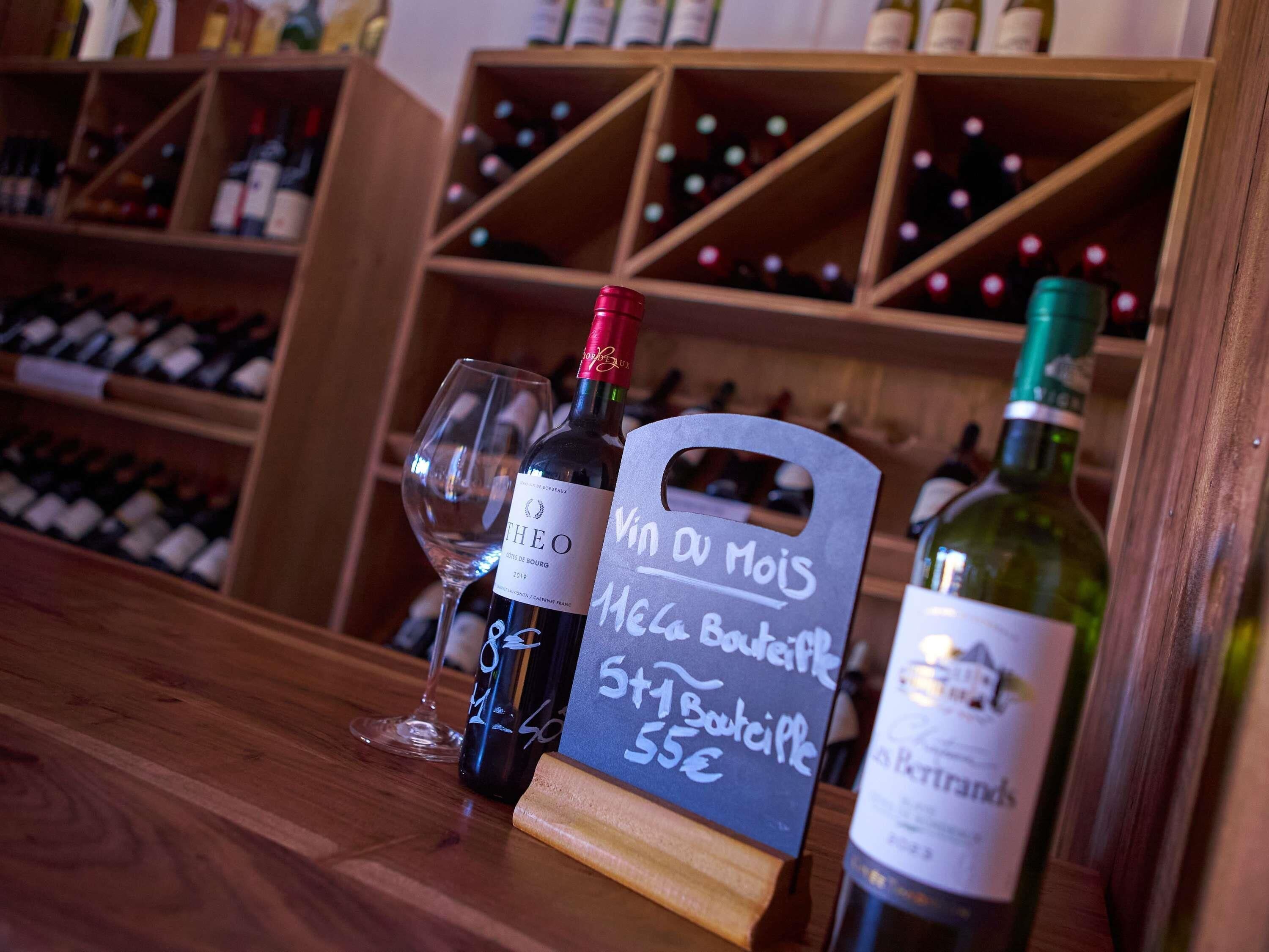 A wine bottle with a label, a wine glass, and a chalkboard sign with text.