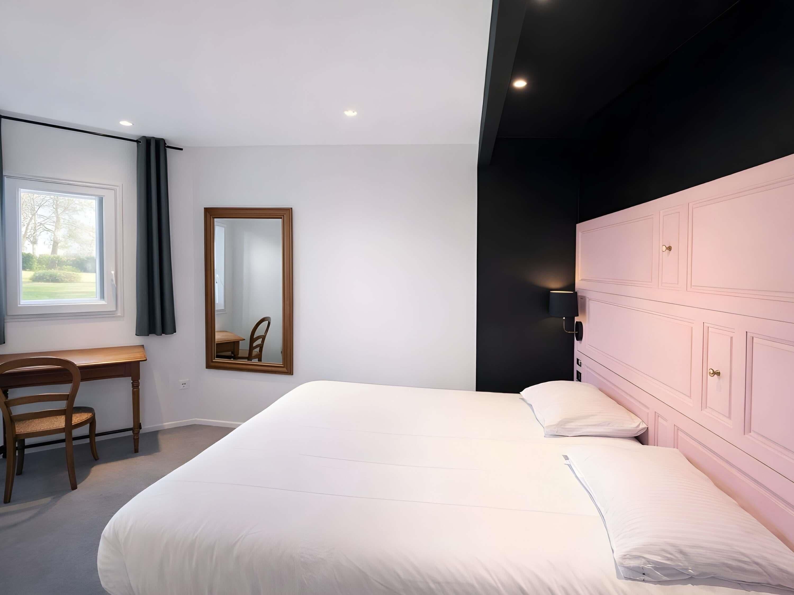 A bedroom with a bed, a desk, a chair, a mirror, and a wardrobe.