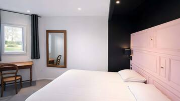 Een slaapkamer met een bed, een bureau, een stoel, een spiegel en een kledingkast.