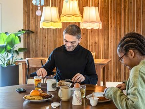 Una mesa de comedor con alimentos para el desayuno, un teléfono inteligente y una planta en maceta.