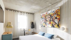 A hotel room with a bed, a desk, a chair, a lamp, a painting, and a window. - greet hotel Limoges Nord (Limoges)