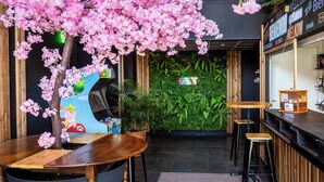 A bar area with a wooden counter, stools, and a decorative pink artificial tree. - greet hotel Limoges Nord (Limoges)