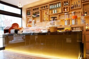 Un bar de hotel con estantes llenos de botellas de licor, una vitrina de vidrio y un mostrador con alimentos.