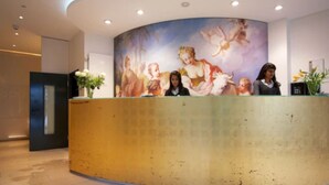 Un comptoir d’accueil, avec une fresque représentant des anges sur le mur qui se trouve derrière.