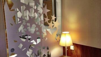 Habitación de hotel con cama, mesita de noche con lámpara y un muro decorado con estrellas.