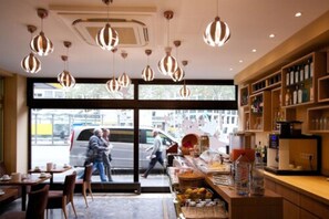 Een café interieur met hangende吊灯, een toonbank met drankjes en een uitzicht op de straat.