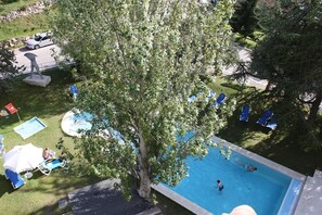 Uima-allasalue, jossa on aurinkotuoleja, puu ja patsas.