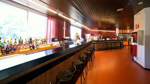 Zona de bar con una barra larga, varios taburetes y una amplia variedad de botellas.