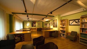 Una biblioteca con mesas y sillas de madera, y estanterías.
