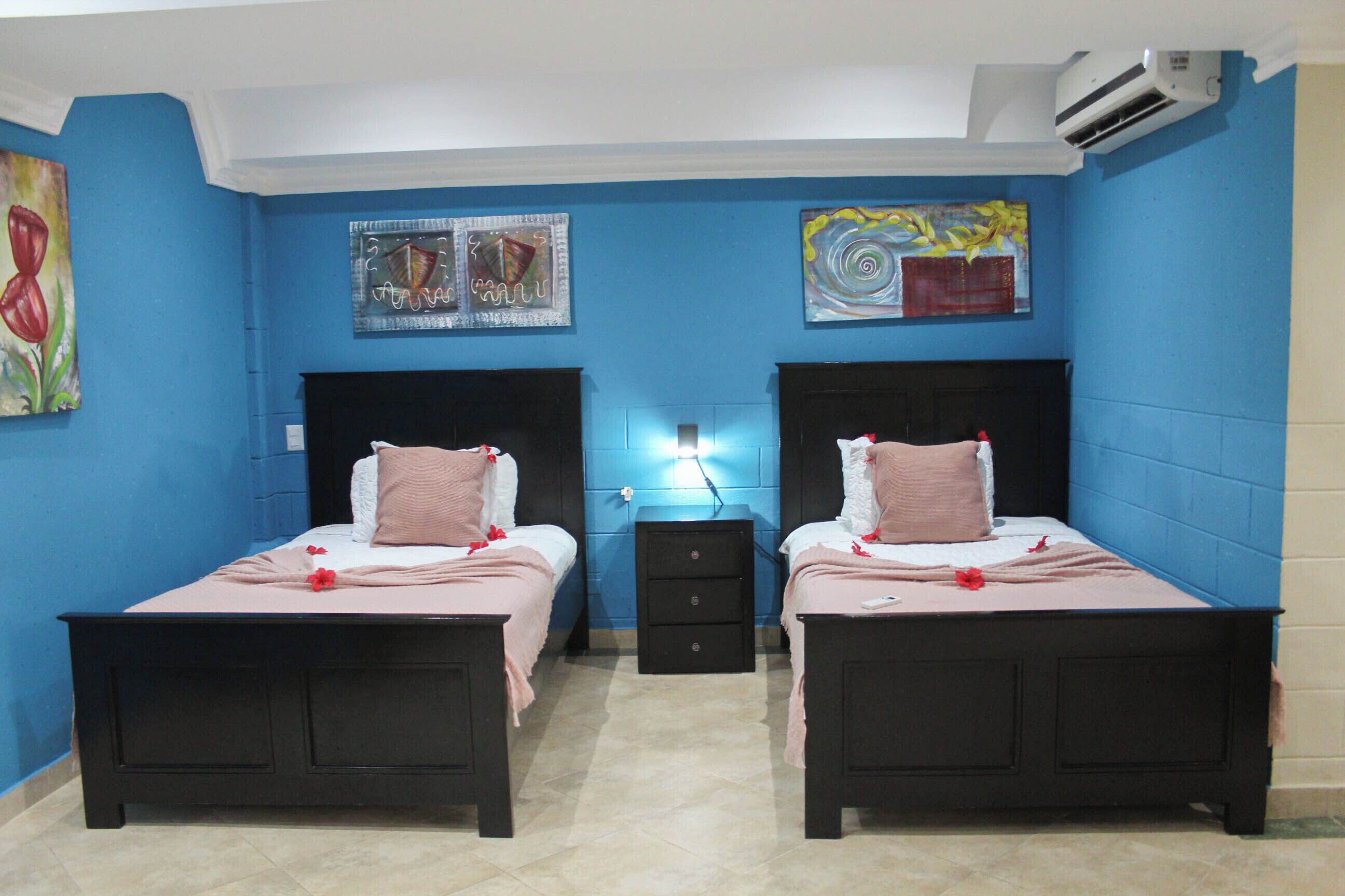 Quarto com duas camas, uma mesa de cabeceira e obras de arte nas paredes.