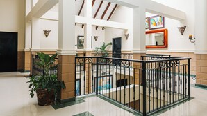 A spacious indoor area with a high ceiling, a staircase, and a potted plant. - The MT Hotel (Punta Cana)