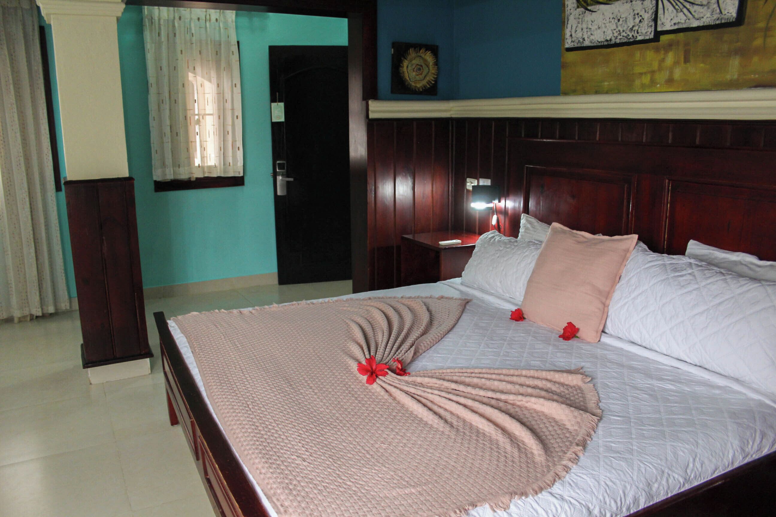 A neatly made bed with a decorative arrangement of pillows and a blanket, a wooden headboard, and a wall clock.