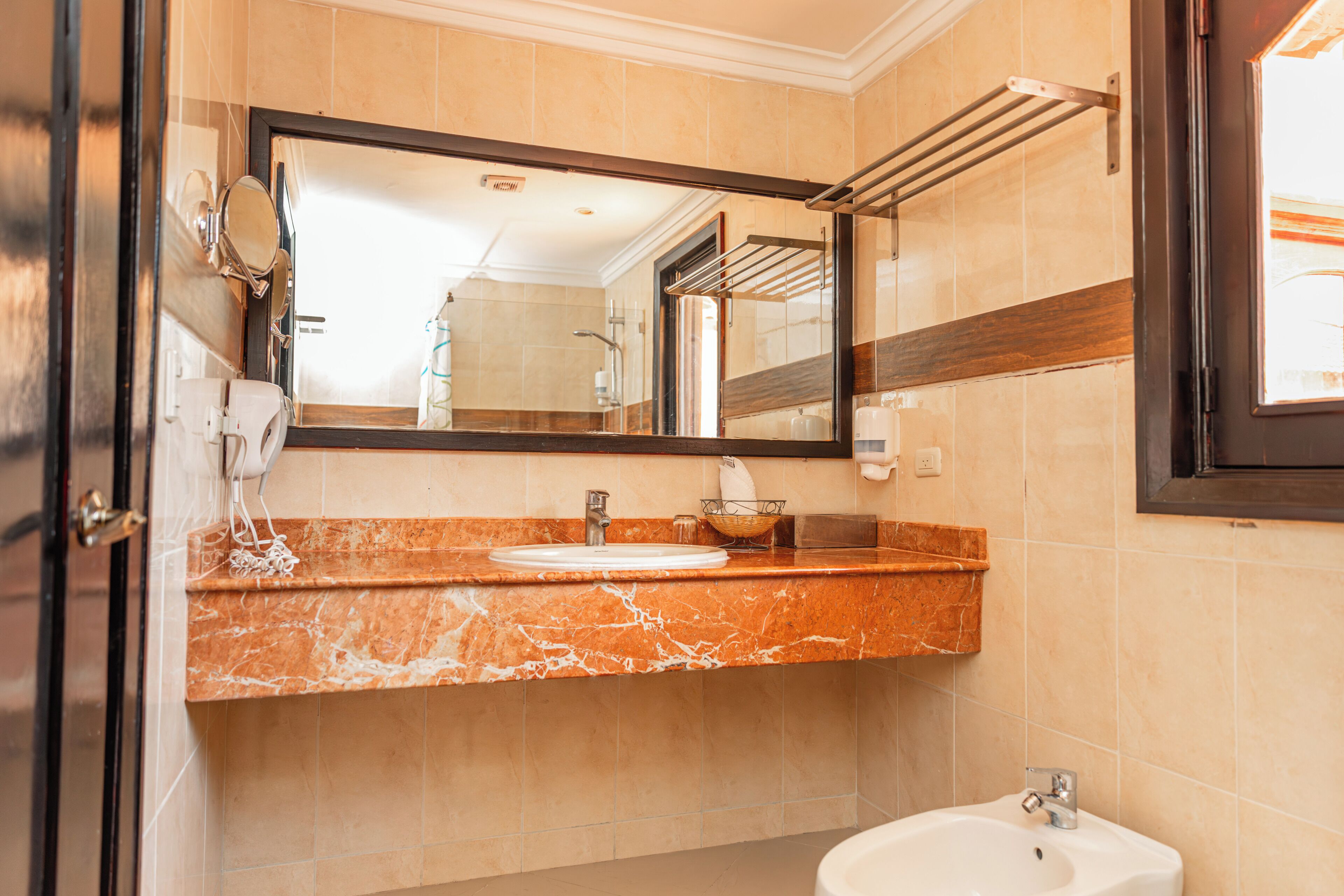 A bathroom with a marble countertop, a sink, a mirror, and a towel rack.
