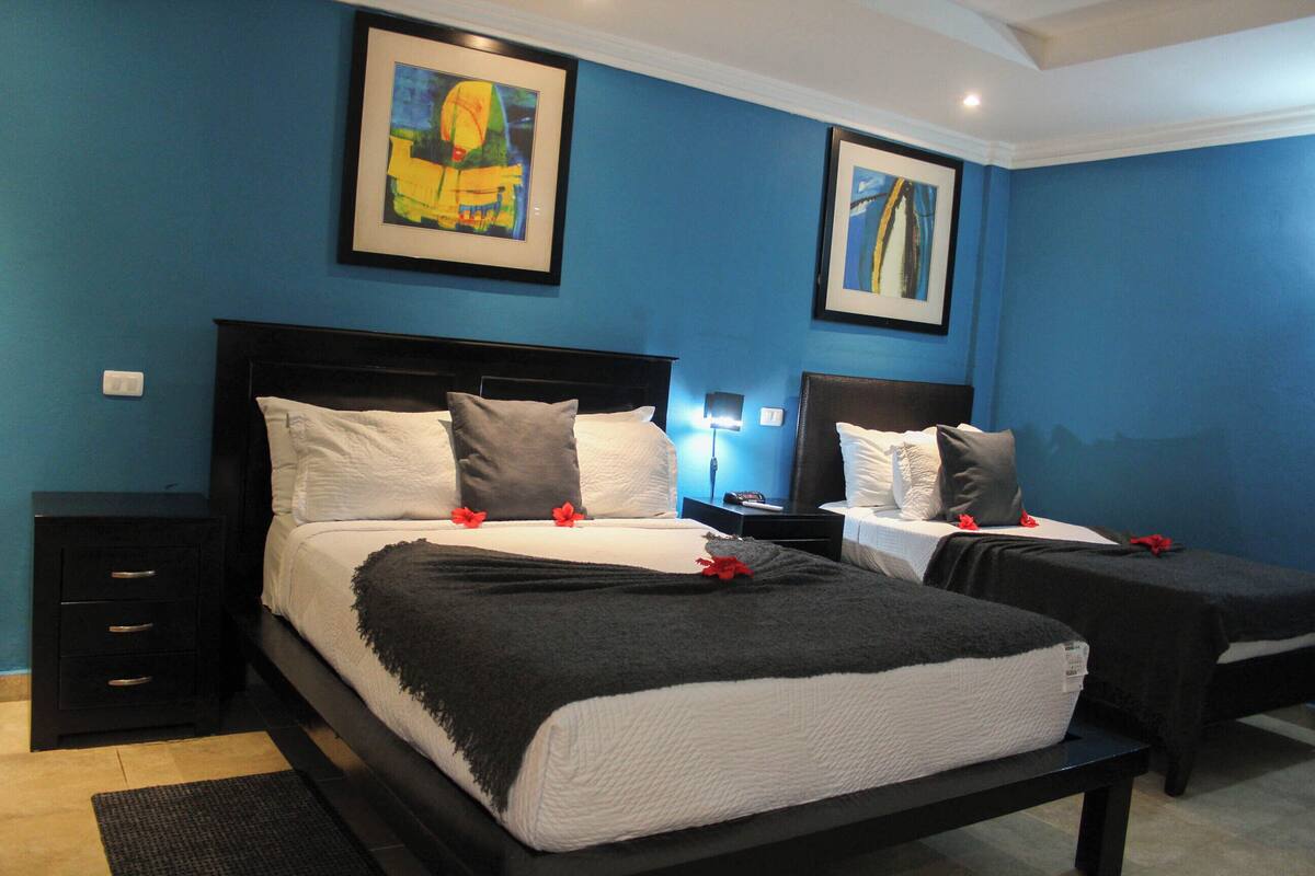 A hotel room with two beds, a dark wooden headboard, white bedding, and artwork on the walls.