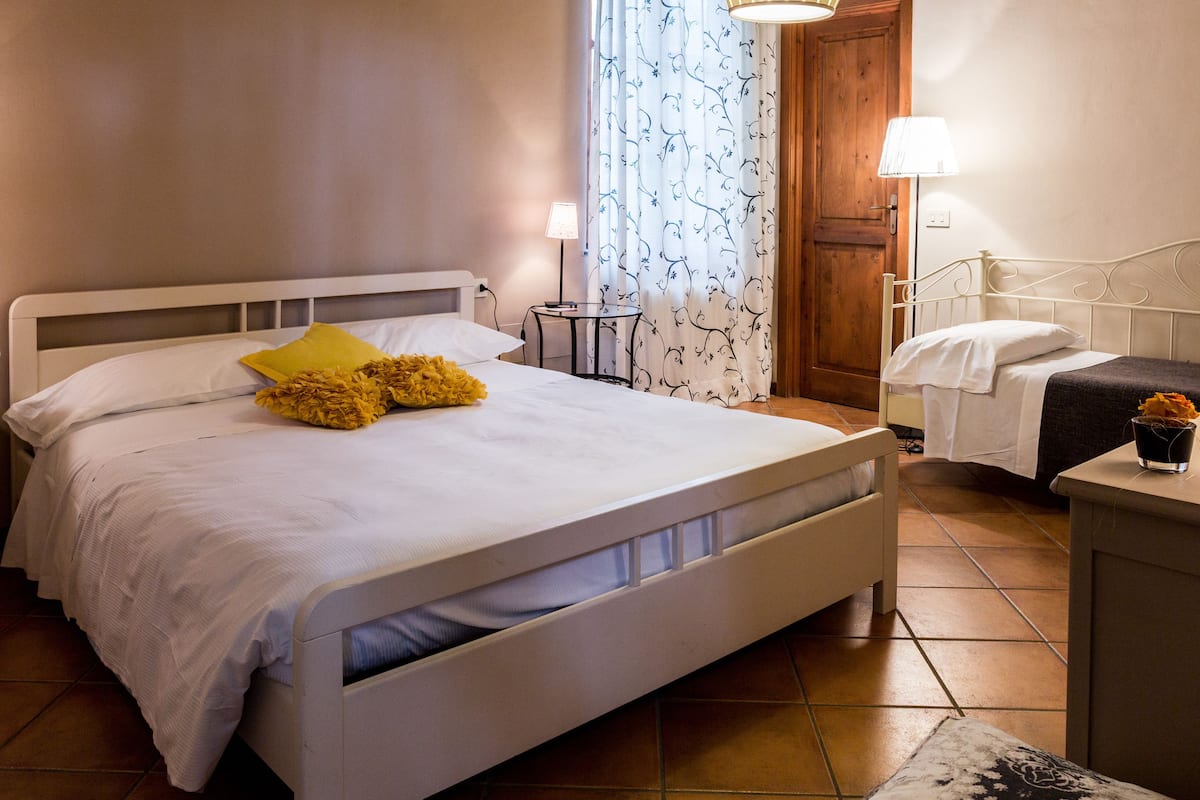 Een slaapkamer met een groot bed, een nachtkastje, een lamp en een houten deur.