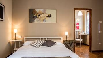 A neatly arranged bedroom with a bed, bedside tables, a chair, and a painting on the wall.
