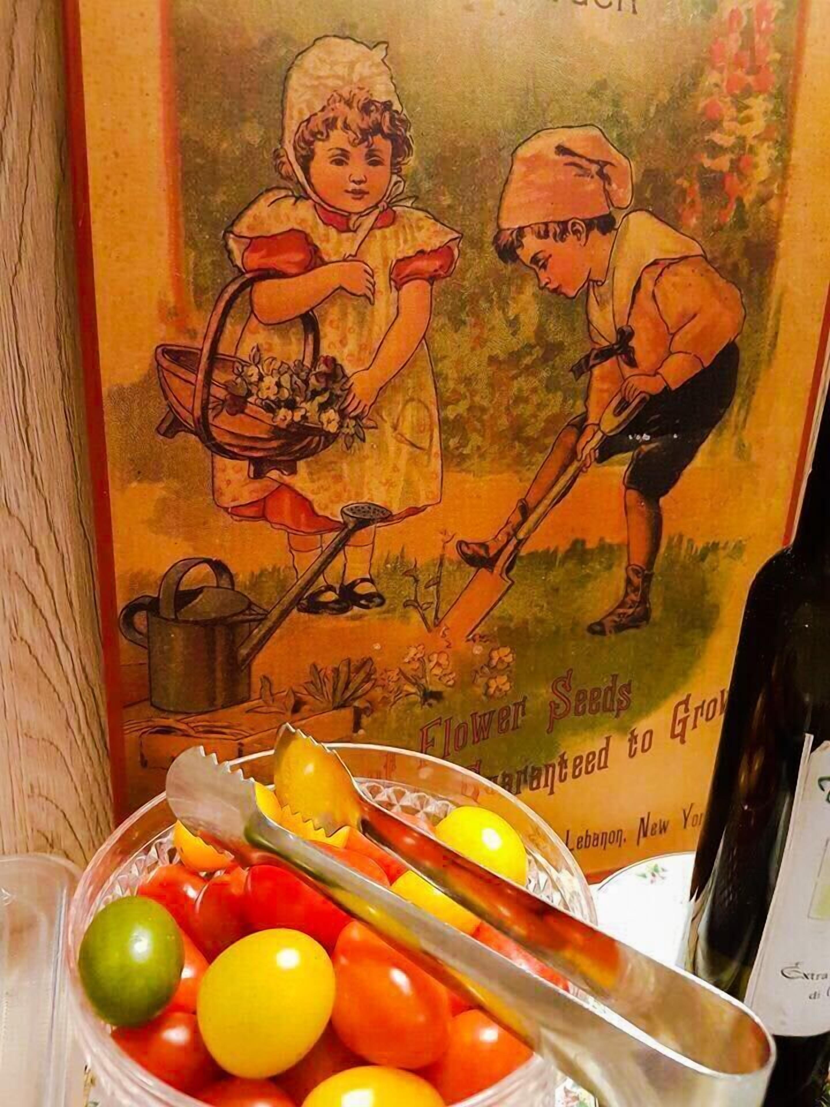 A bowl of colorful cherry tomatoes with a vintage poster in the background.