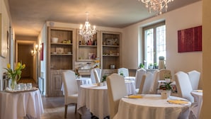 Un espace repas avec des tables rondes, des chaises blanches et des lustres.
