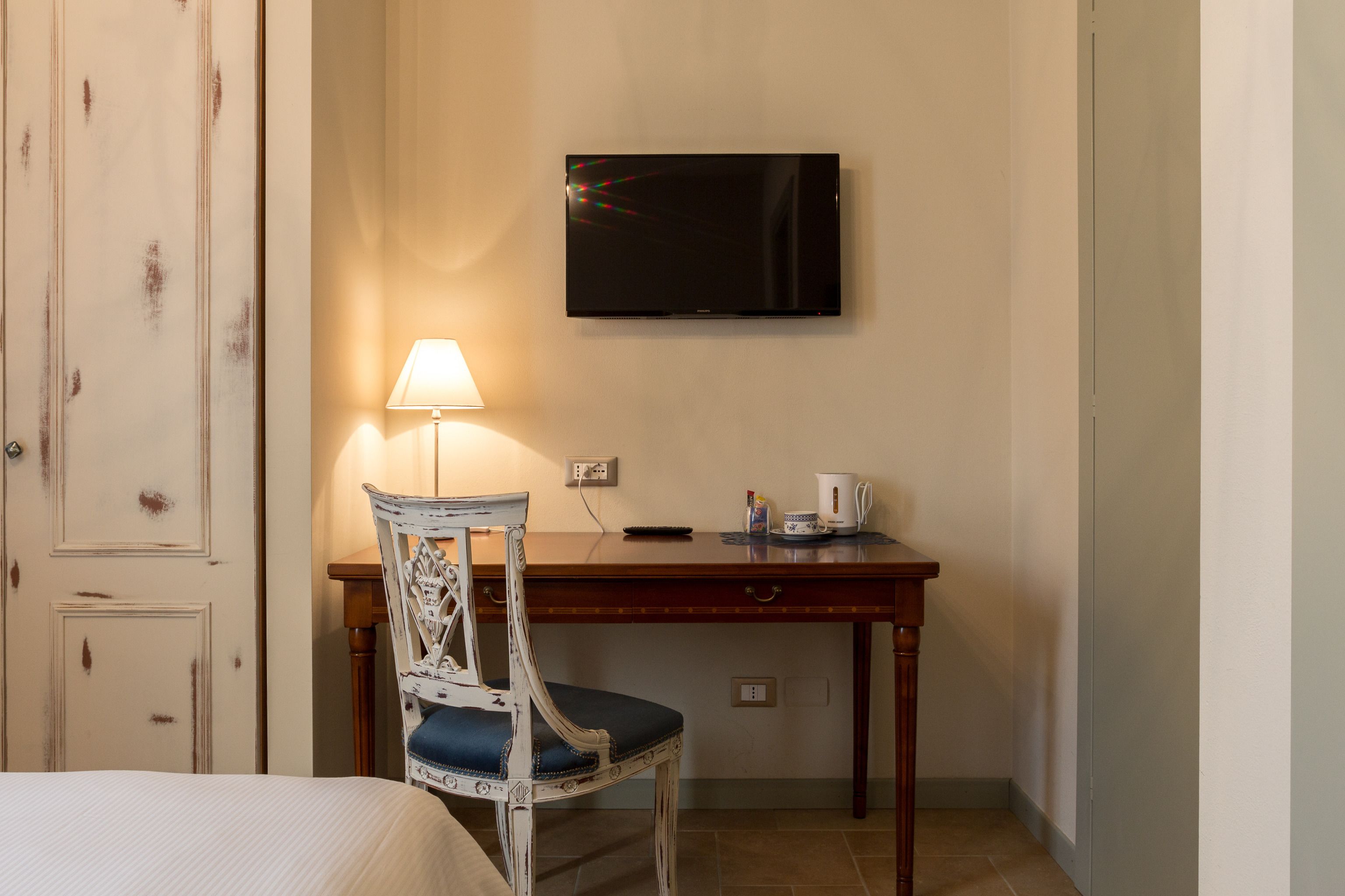 Ein Hotelzimmer mit einem Bett, einem Holztisch mit Lampe, einem Fernseher und einem Sessel.