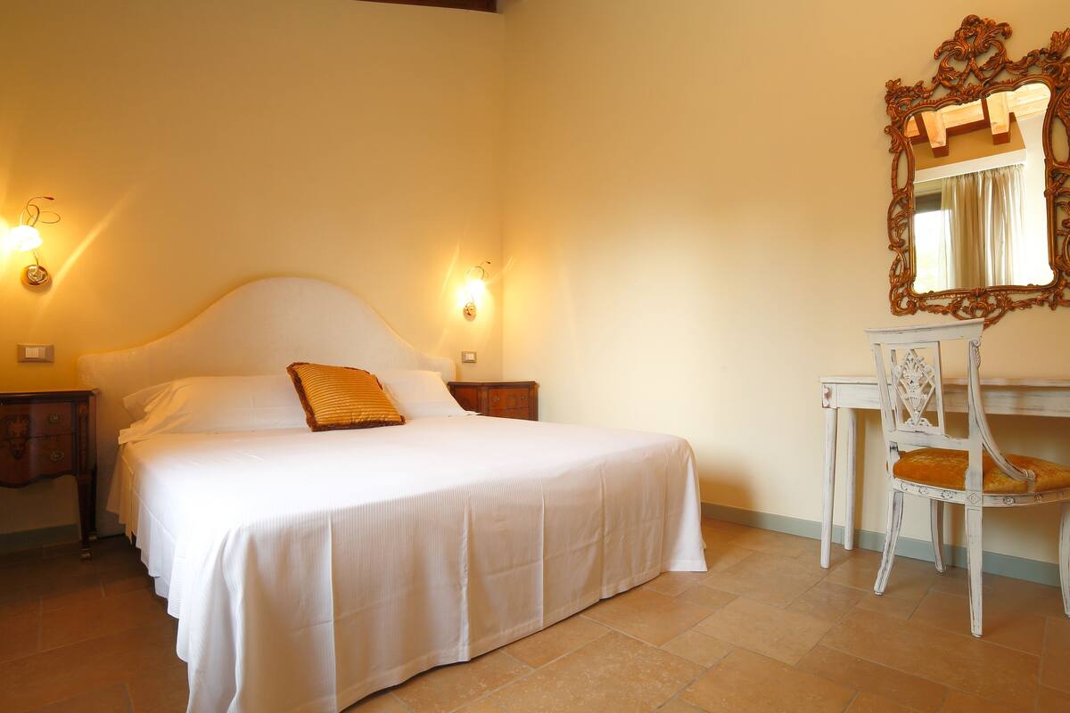 Een slaapkamer met een bed, bureau en spiegel.