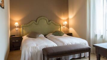 A double bed with a wooden headboard, two bedside tables with lamps, and a bench.