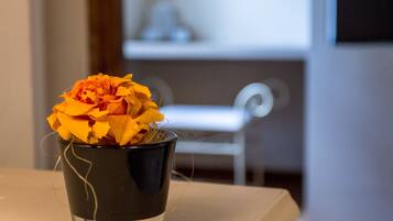 A black vase with a yellow flower on a table.