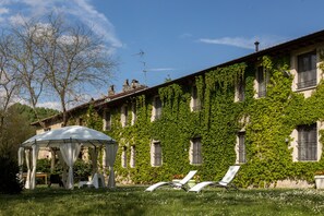 Un bâtiment dont les murs sont recouverts de lierre et qui dispose d’un espace extérieur abrité avec des chaises.