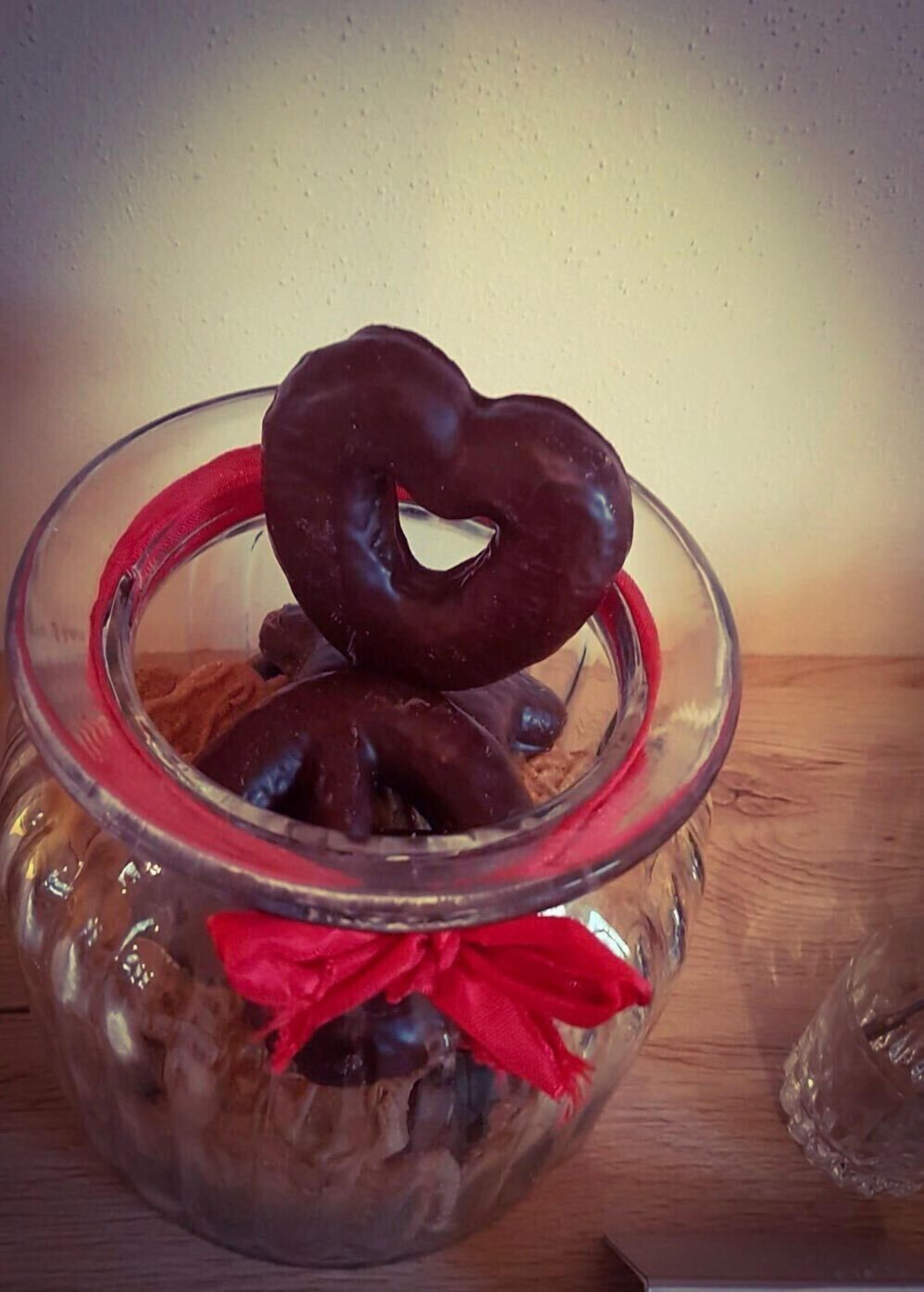 A glass bowl containing chocolate-covered doughnuts and a heart-shaped doughnut.