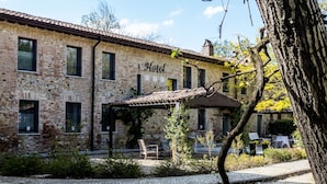 Un bâtiment en pierre avec une enseigne indiquant « Hôtel » et un espace extérieur abrité avec des chaises et des tables.