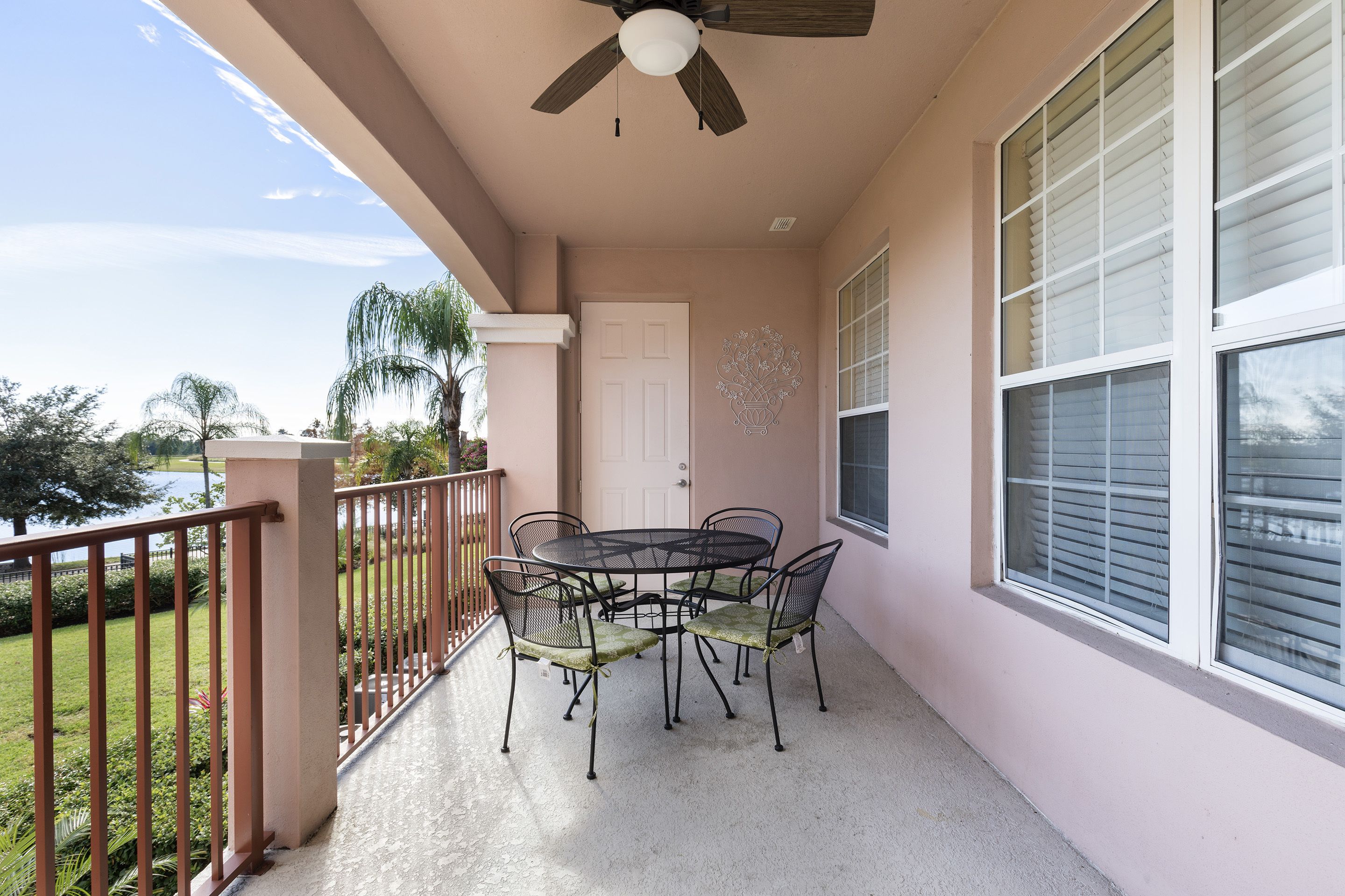 A balcony with a table and chairs, a ceiling fan, and a view of the outdoors.