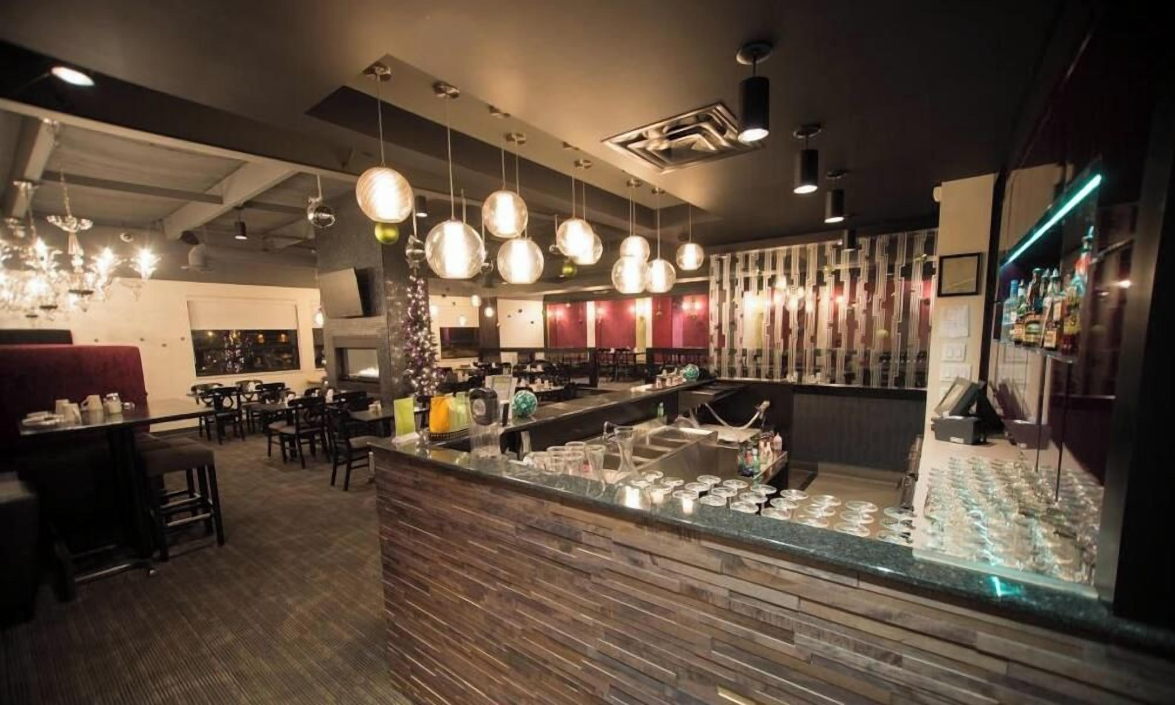 Un'area bar con un bancone, luci a sospensione e posti a sedere.