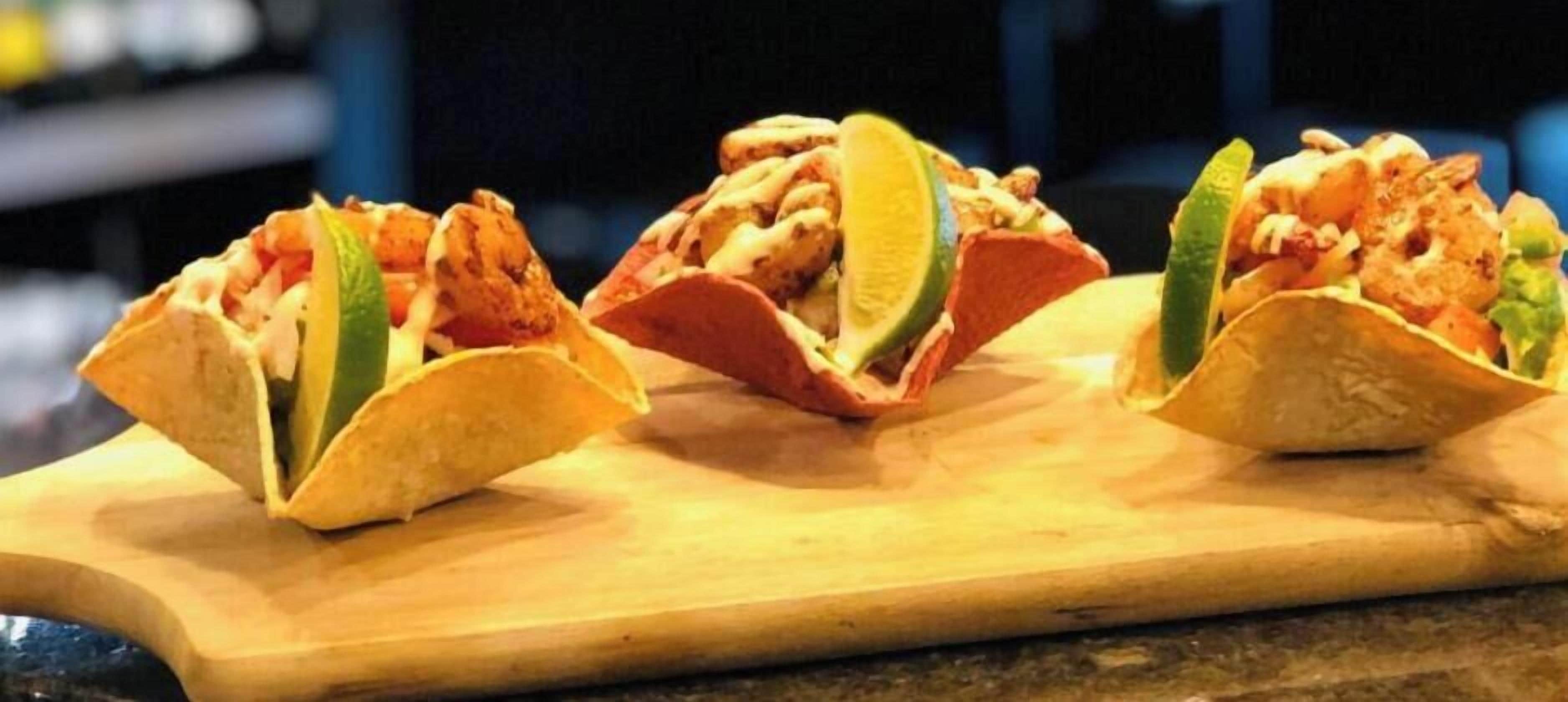 Tres tacos sobre una tabla de madera.