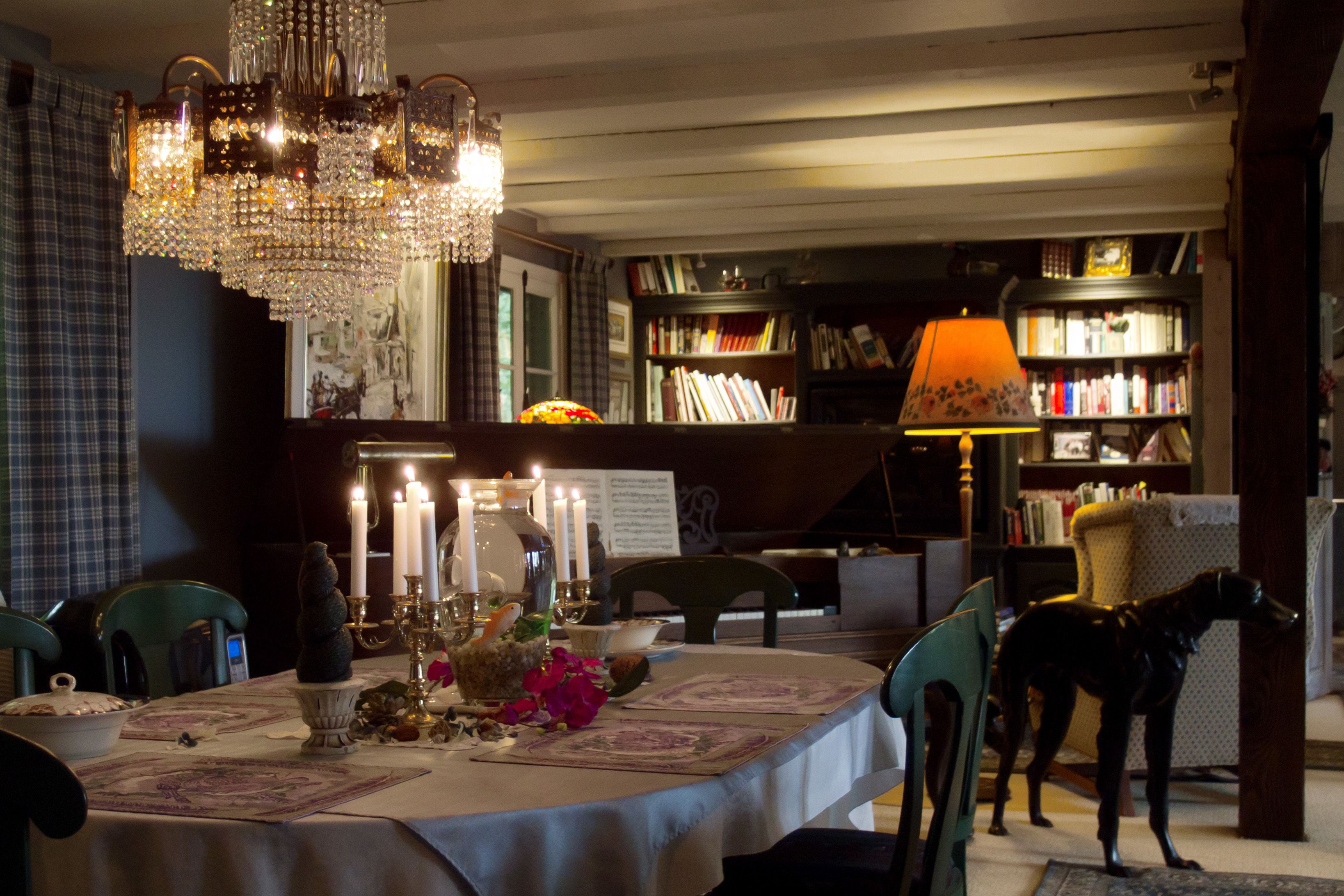 Un coin repas agrémenté d’un lustre, d’une table décorée de bougies et d’un chien qui se tient près de la porte.