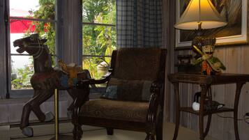 A room with a wooden chair, a lamp, and a horse sculpture near a window.