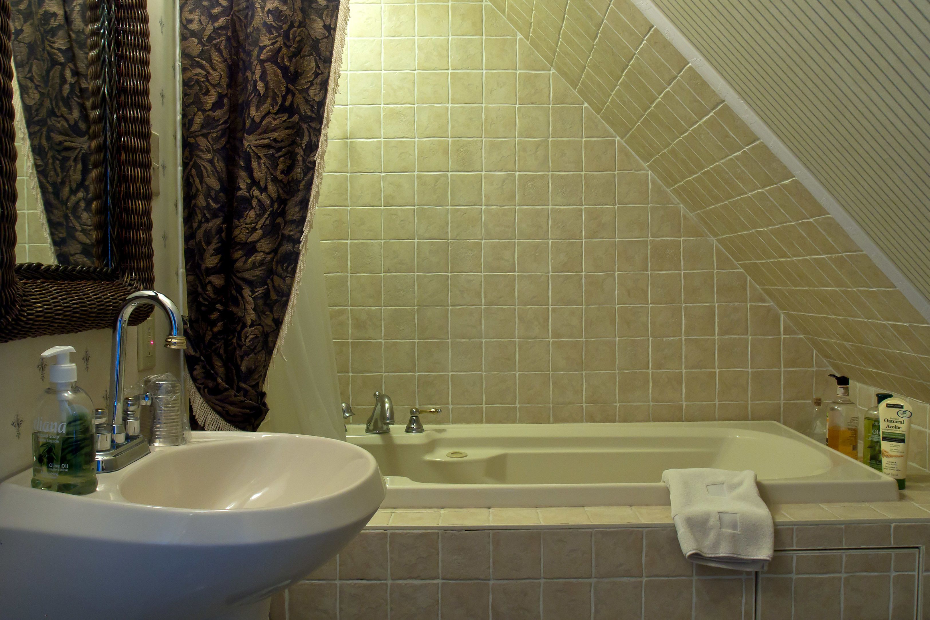 A bathroom with a sink, bathtub, and shower curtain.
