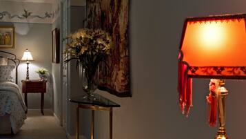 Une chambre à coucher avec un lit, une table de chevet avec une lampe, un vase de fleurs et un tableau accroché au mur.