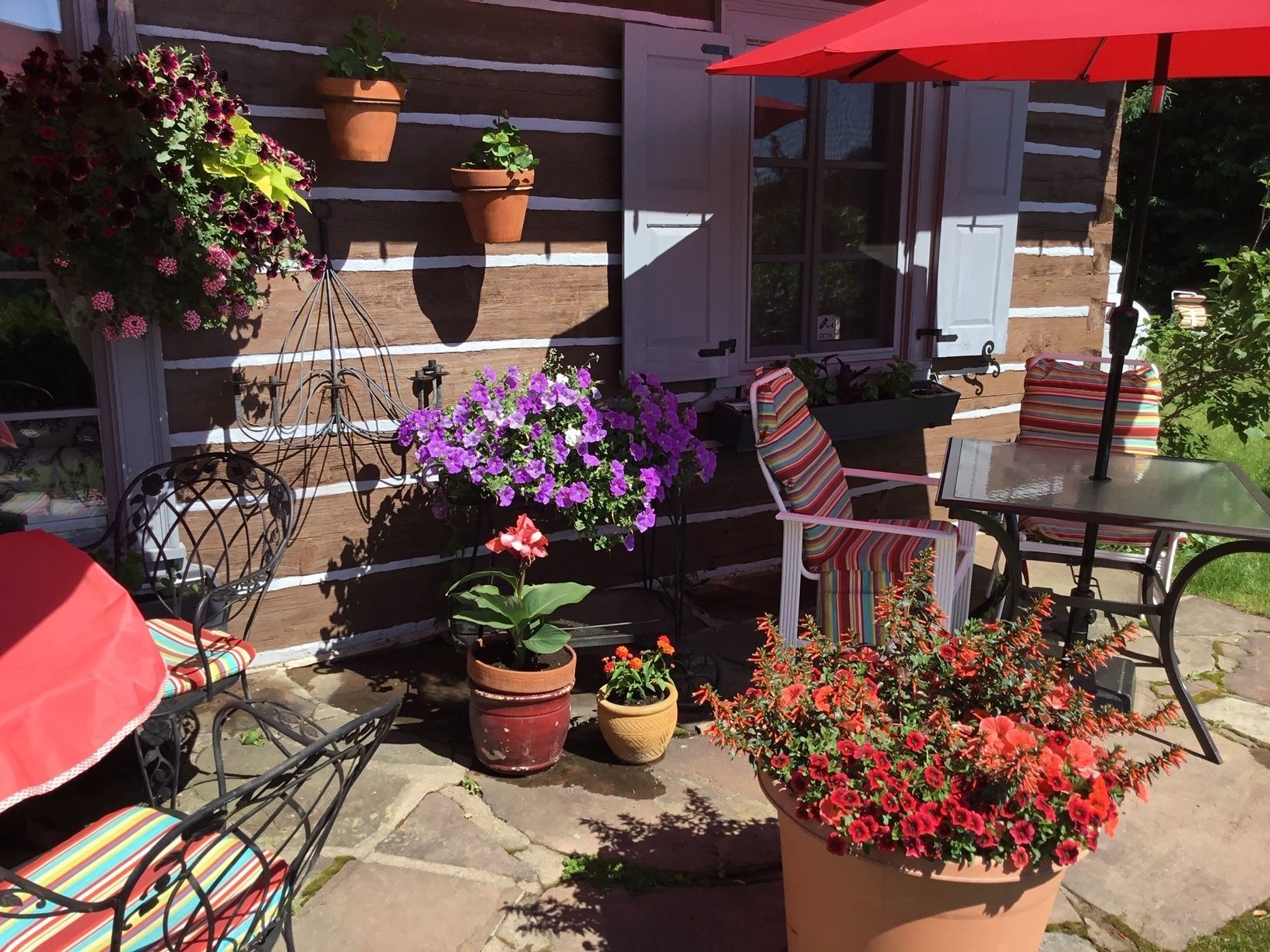 A patio with outdoor furniture, potted plants, and a striped chair.