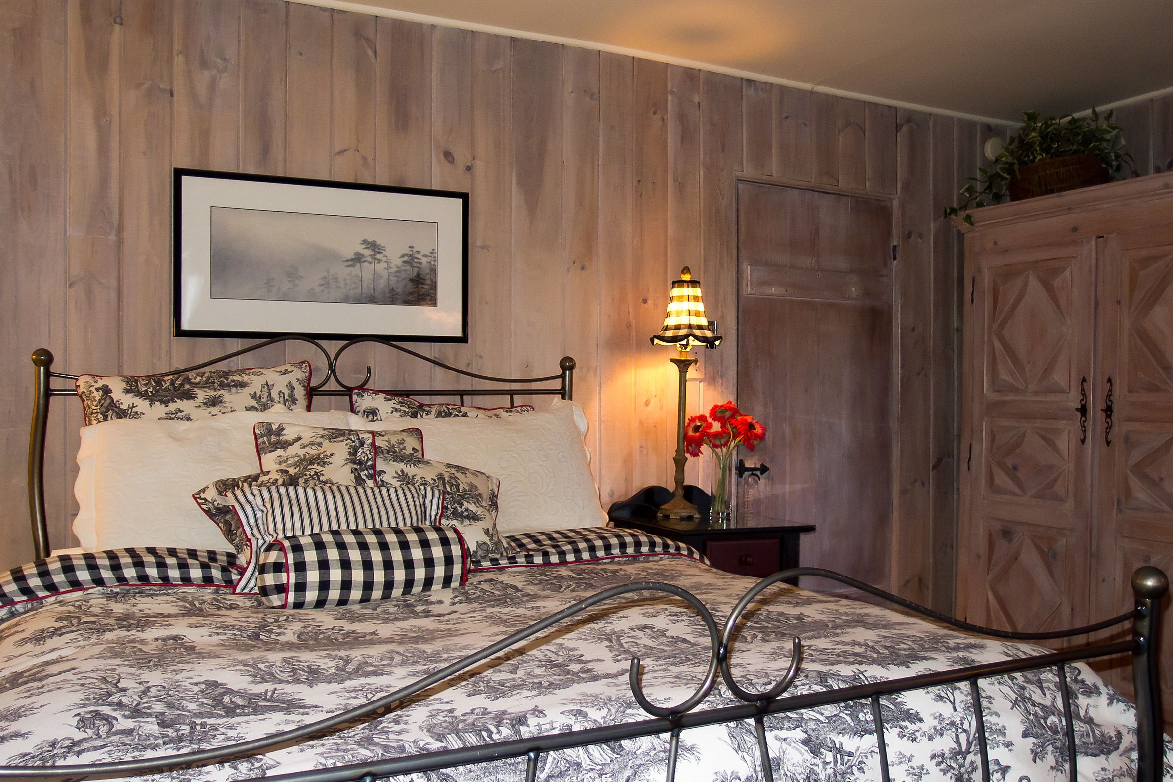 Un lit bien fait, avec une literie à motifs floraux, une table de chevet avec une lampe et une armoire en bois.