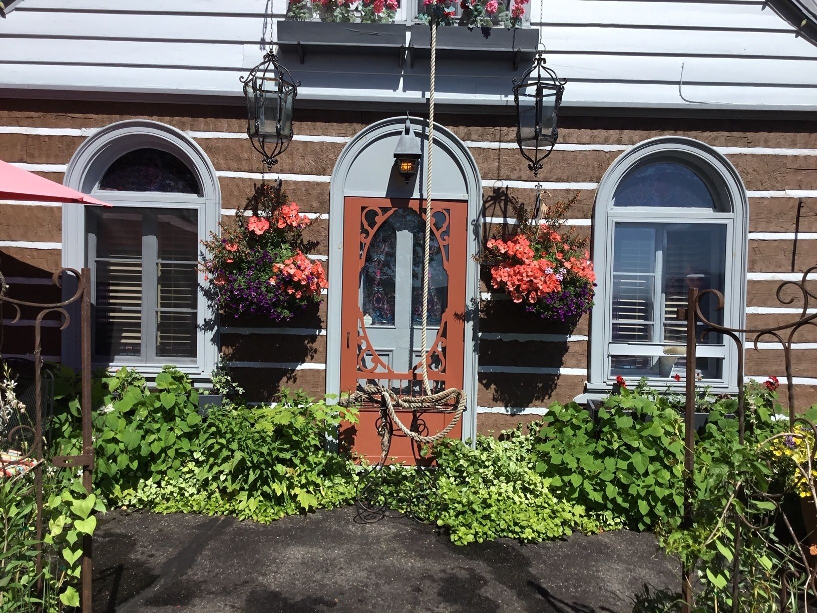 Un edificio con una puerta central, flanqueada por dos ventanas con jardineras.